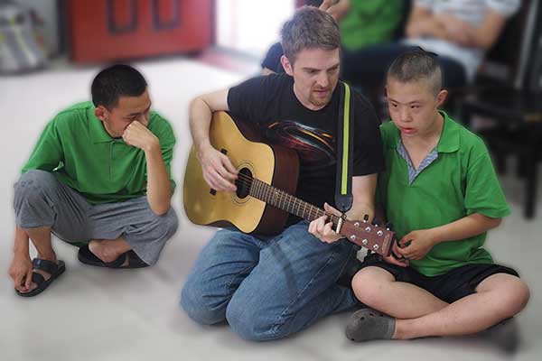 young man playing guitar with another man