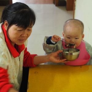 Child carer feeding baby
