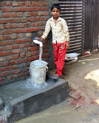 Fresh water bore well in India with boy drinking