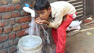 Indian boy drinking from water tap